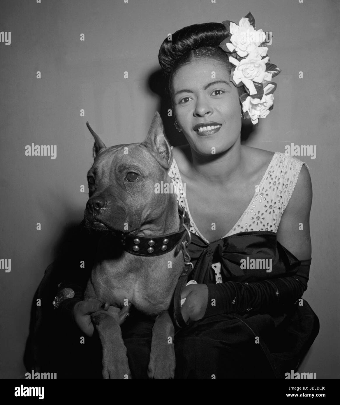 Billie Holiday e il suo cane Mister nello spogliatoio del Club Downbeat a febbraio 1947. Billie Holiday, nata Eleanora Fagan (New York, 7 aprile 1915 – New York, 17 luglio 1959), è stata una cantante statunitense di musica jazz e swing. Soprannominata "Lady Day" dalla sua amica e partner musicale, Lester Young, Holiday ha dato un contributo significativo alla musica jazz e al canto pop. Il suo stile vocale, fortemente influenzato dagli strumentisti jazz, ha ispirato un nuovo modo di manipolare il fraseggio e il tempo. Holiday era nota per le sue doti vocali e improvvisative Foto Stock