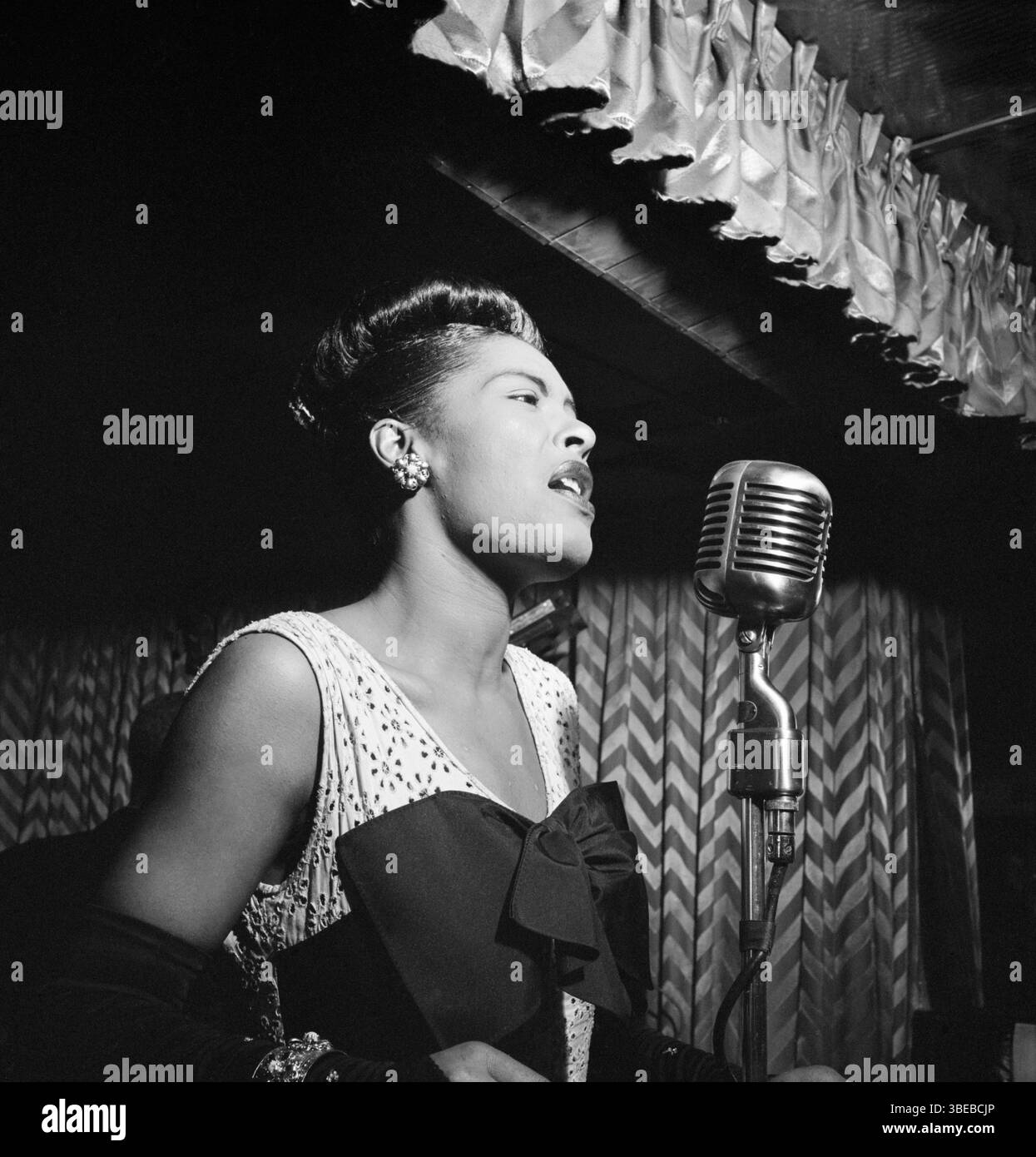Billie Holiday canta al Club Downbeat il 52 febbraio 1947. Billie Holiday, nata Eleanora Fagan (New York, 7 aprile 1915 – New York, 17 luglio 1959), è stata una cantante statunitense di musica jazz e swing. Soprannominata "Lady Day" dalla sua amica e partner musicale, Lester Young, Holiday ha dato un contributo significativo alla musica jazz e al canto pop. Il suo stile vocale, fortemente influenzato dagli strumentisti jazz, ha ispirato un nuovo modo di manipolare il fraseggio e il tempo. Holiday era nota per le sue doti vocali e improvvisative. Foto di William Gottlieb. Foto Stock