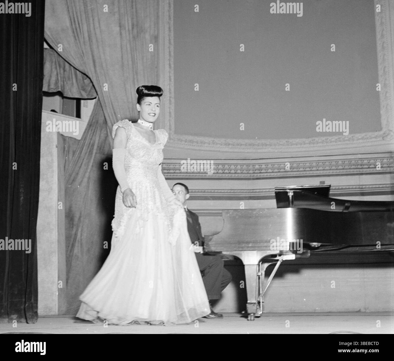 Billie Holiday alla Carnegie Hall, New York, N.Y., tra il 1946 e il 1948. Billie Holiday, nata Eleanora Fagan (New York, 7 aprile 1915 – New York, 17 luglio 1959), è stata una cantante statunitense di musica jazz e swing. Soprannominata "Lady Day" dalla sua amica e partner musicale, Lester Young, Holiday ha dato un contributo significativo alla musica jazz e al canto pop. Il suo stile vocale, fortemente influenzato dagli strumentisti jazz, ha ispirato un nuovo modo di manipolare il fraseggio e il tempo. Holiday era nota per le sue doti vocali e improvvisative Foto Stock