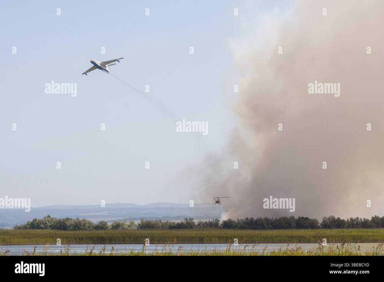 Estinguere il fuoco dall'aria utilizzando un aereo e un elicottero, con la combustione di canne sulle pianure alluvionali del fiume Anapka, Anapa, Russia, E. Foto Stock