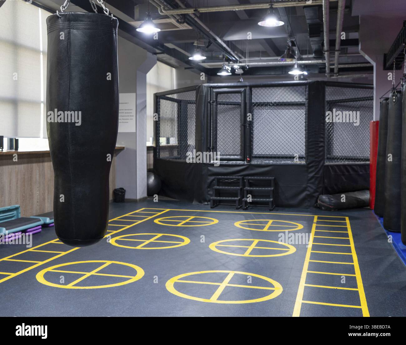 Una gabbia di kickboxing ottagonale con sacchetti di boxe nel complesso sportivo Foto Stock