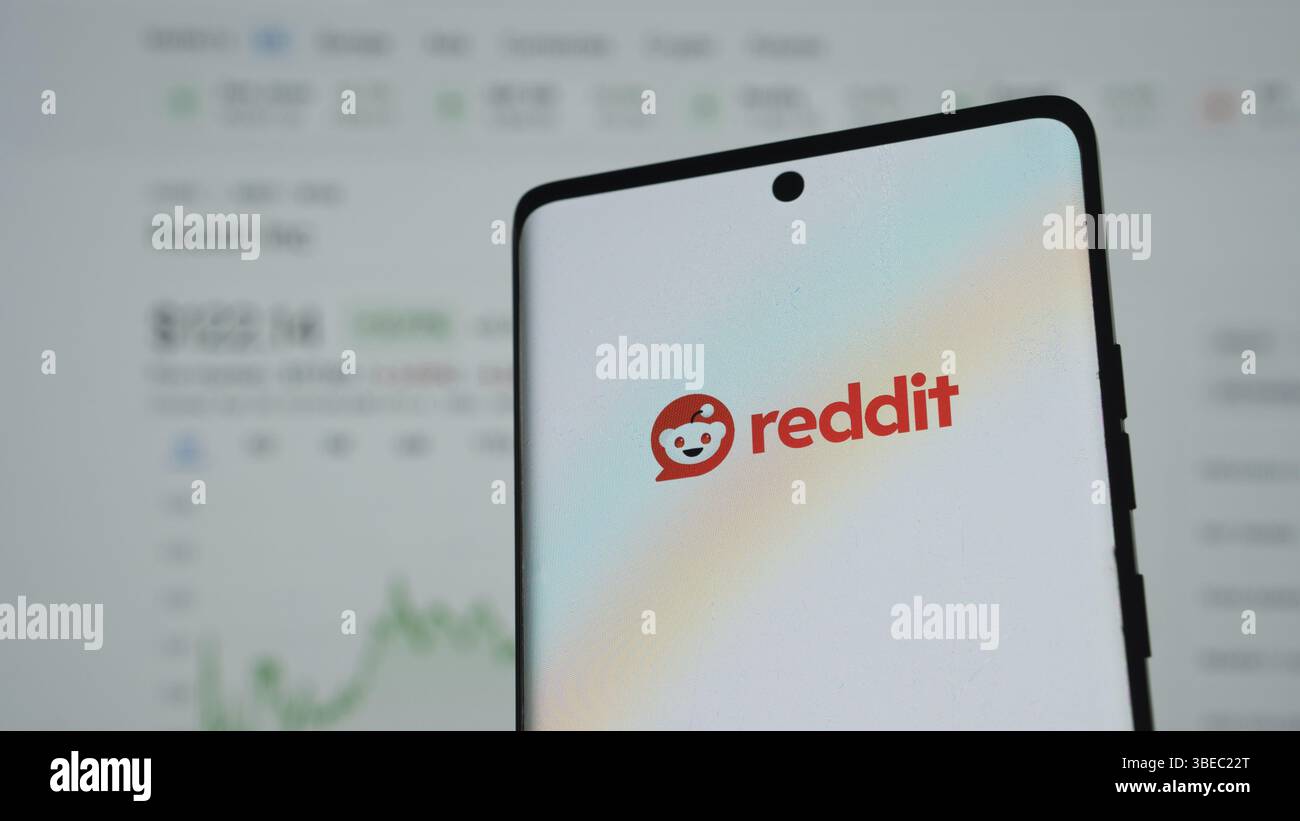 Smartphone con logo Reddit e sfondo sfocato di dati finanziari Foto Stock
