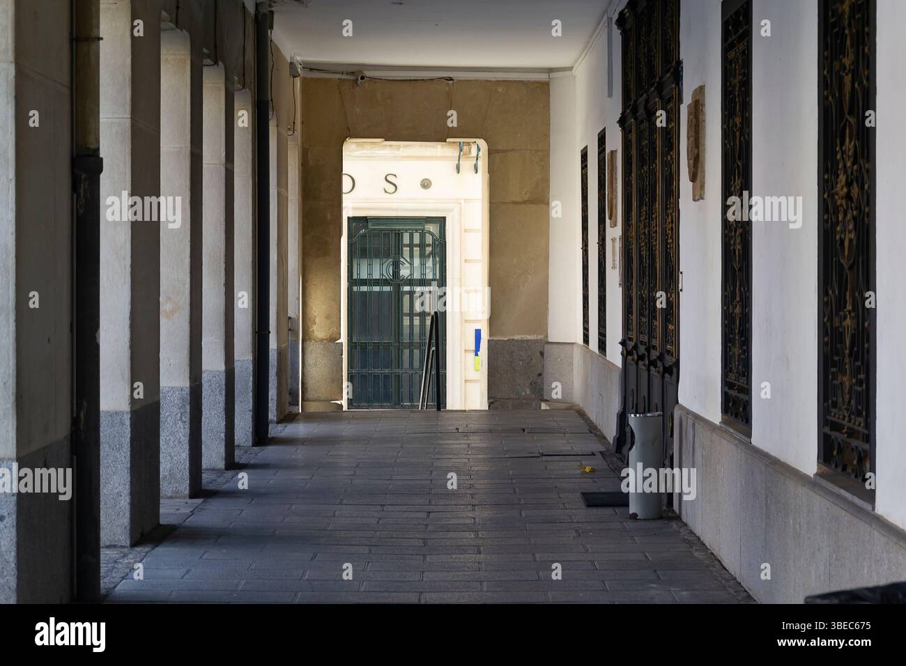 Gli archi fiancheggiano il corridoio, guidando la vista verso una porta verde che invita all'esplorazione alla luce del giorno. Foto Stock