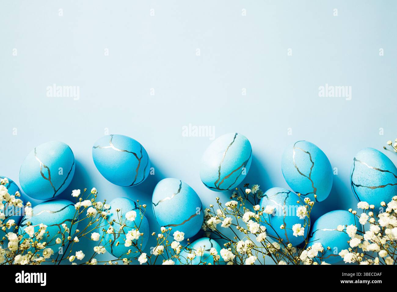 Biglietto di auguri di buona Pasqua. Composizione piatta con eleganti uova di Pasqua con fiori su sfondo blu. Foto Stock
