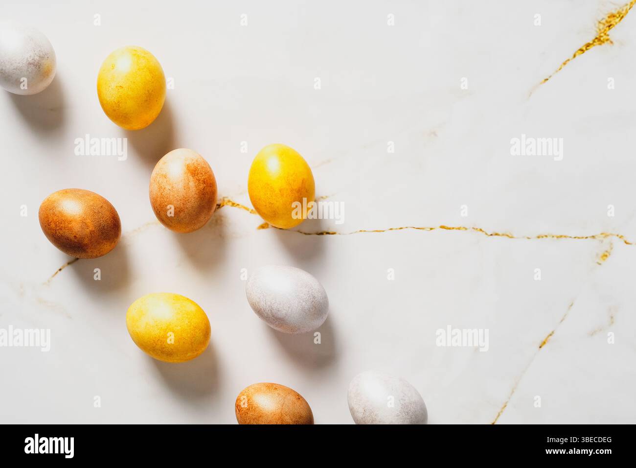 Elegante composizione pianeggiante pasquale. Uova di Pasqua in bronzo di lusso su un tavolo di marmo. Disposizione piatta, vista dall'alto. Foto Stock