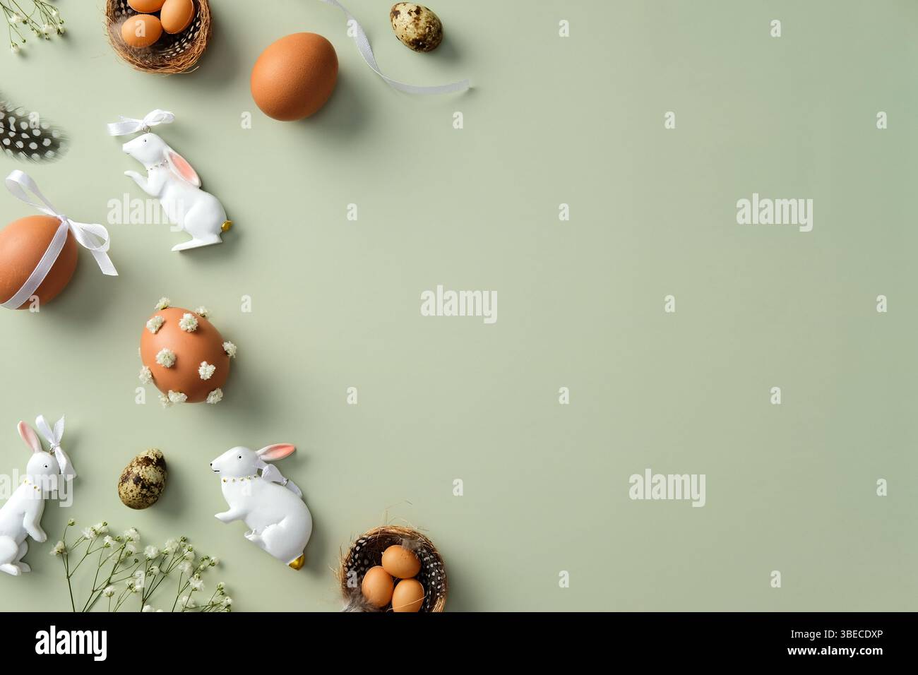Concetto di buona Pasqua. Composizione piatta con uova di Pasqua, uova di quaglia, fiori di gitsofila, coniglietti pasquali, piume su sfondo verde pastello Foto Stock