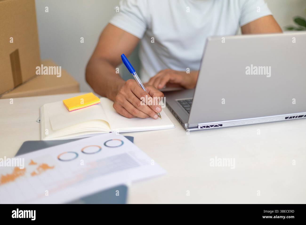 primo piano di un uomo concentrato che lavora in multitasking con un notebook e un notebook che gestiscono un'azienda locale Foto Stock