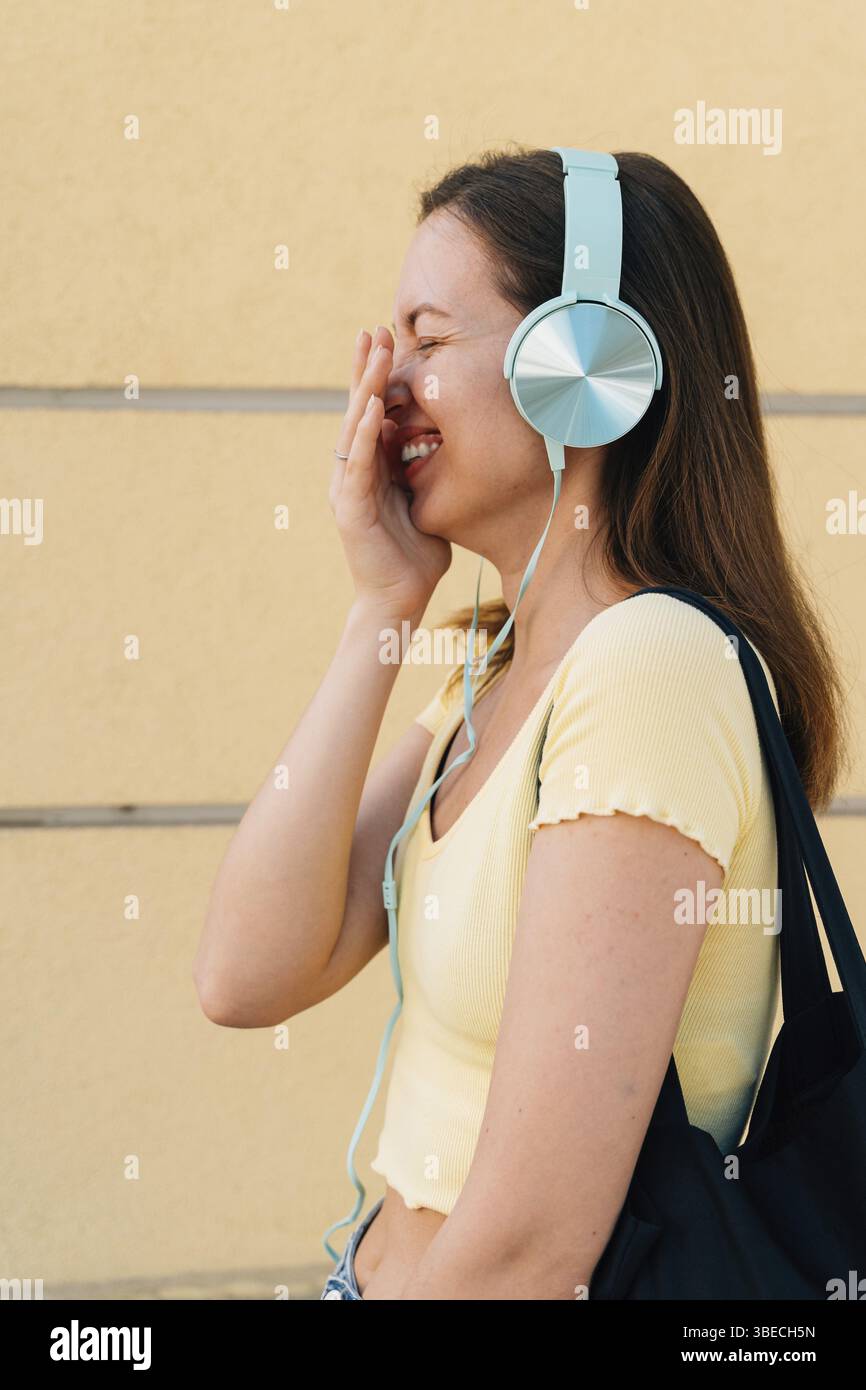 Giovane donna con cuffie Mint e cappuccio nero all'esterno della strada. Foto Stock