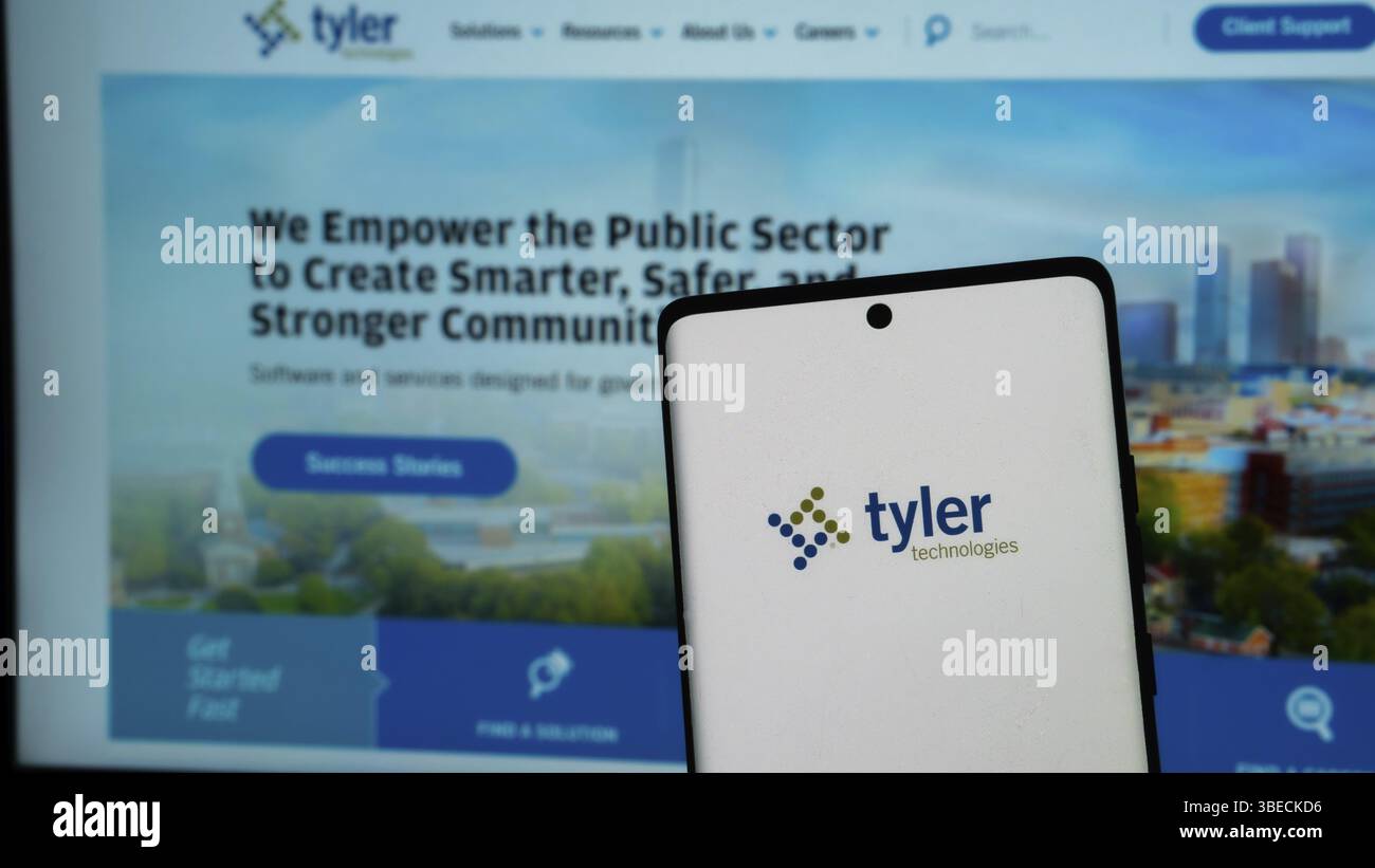 Smartphone con logo Tyler Technologies davanti a un sito Web di soluzioni per il settore pubblico Foto Stock