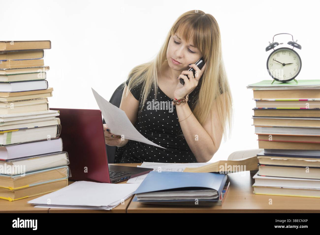 Teacher discusses by phone written on a sheet of paper Foto Stock