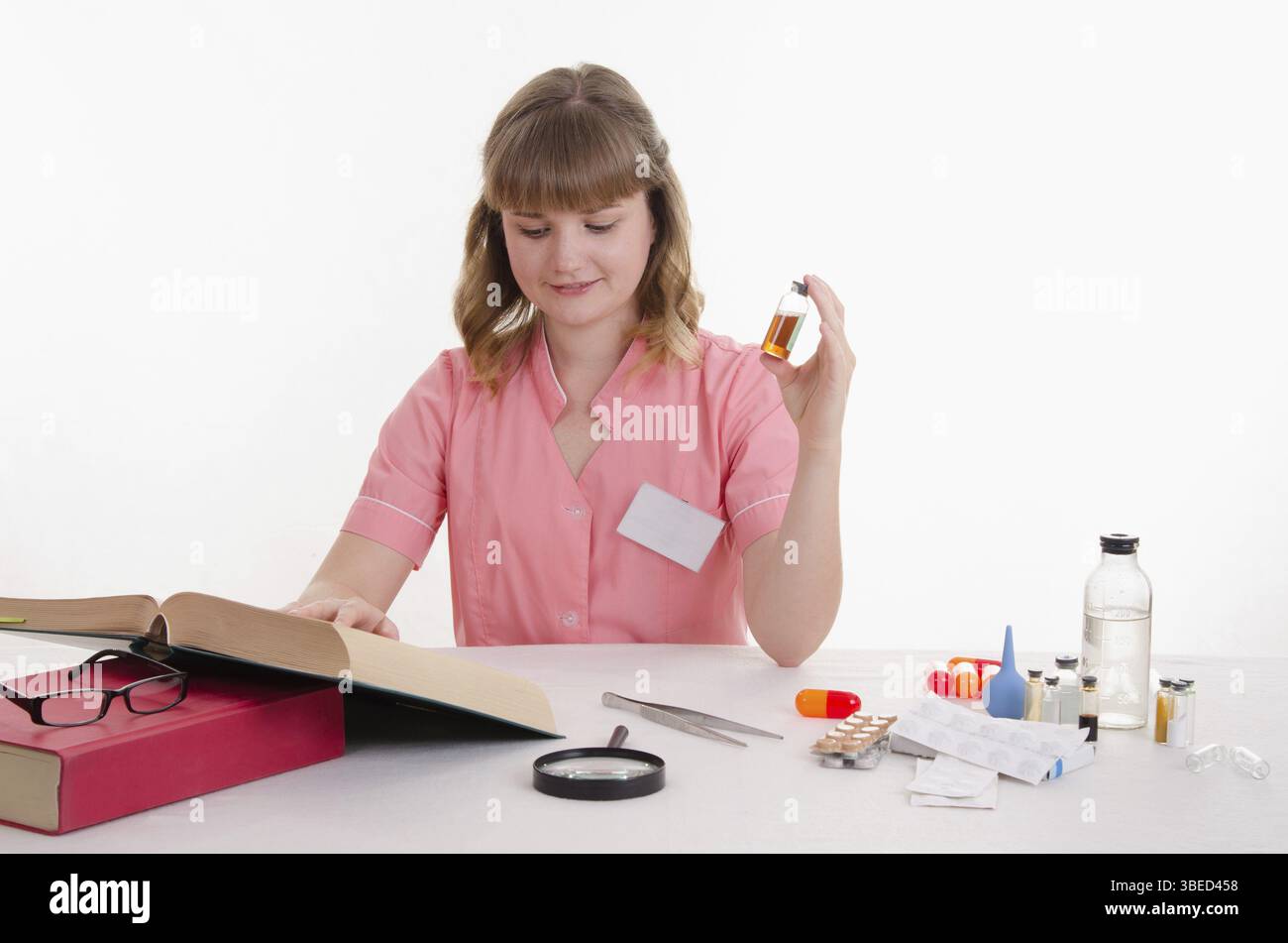 Il farmacista seduti a tavola la lettura di una spessa Handbook of Medicine Foto Stock