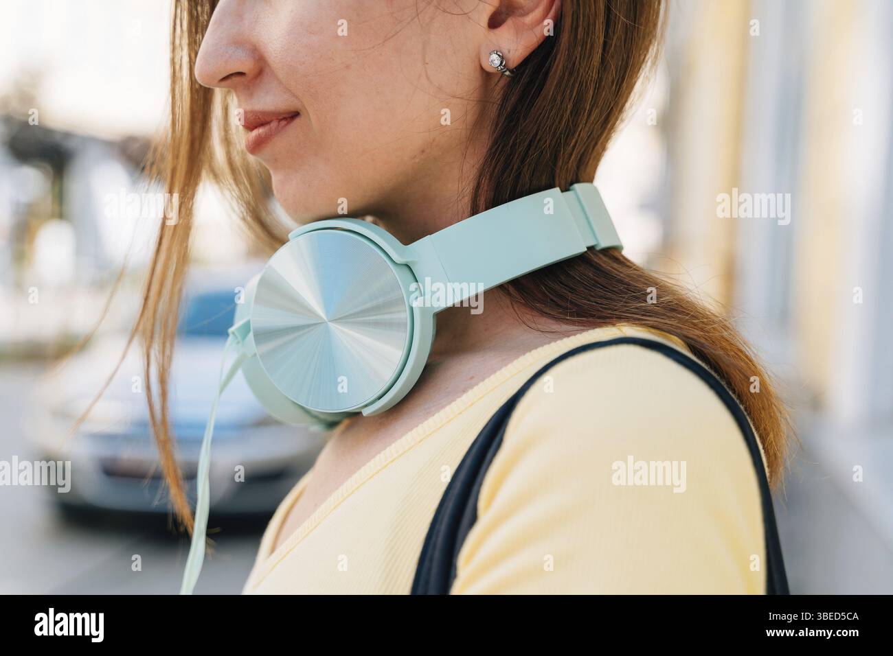 Giovane donna con cuffie Mint e cappuccio nero all'esterno della strada. Foto Stock