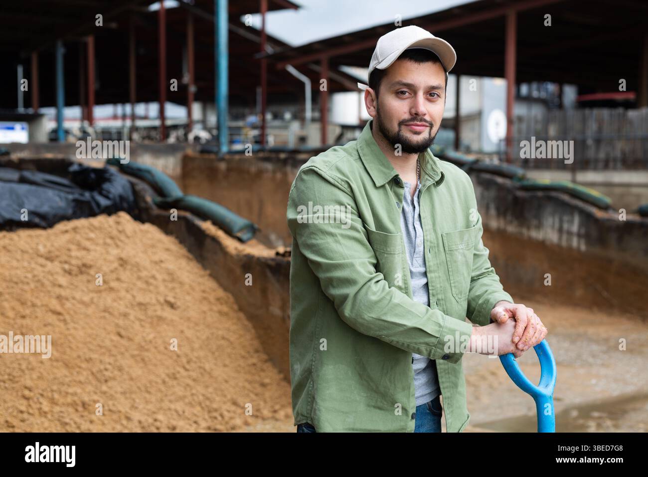 Contadino in piedi in fattoria all'aperto vicino al mucchio di bagasse di birra Foto Stock