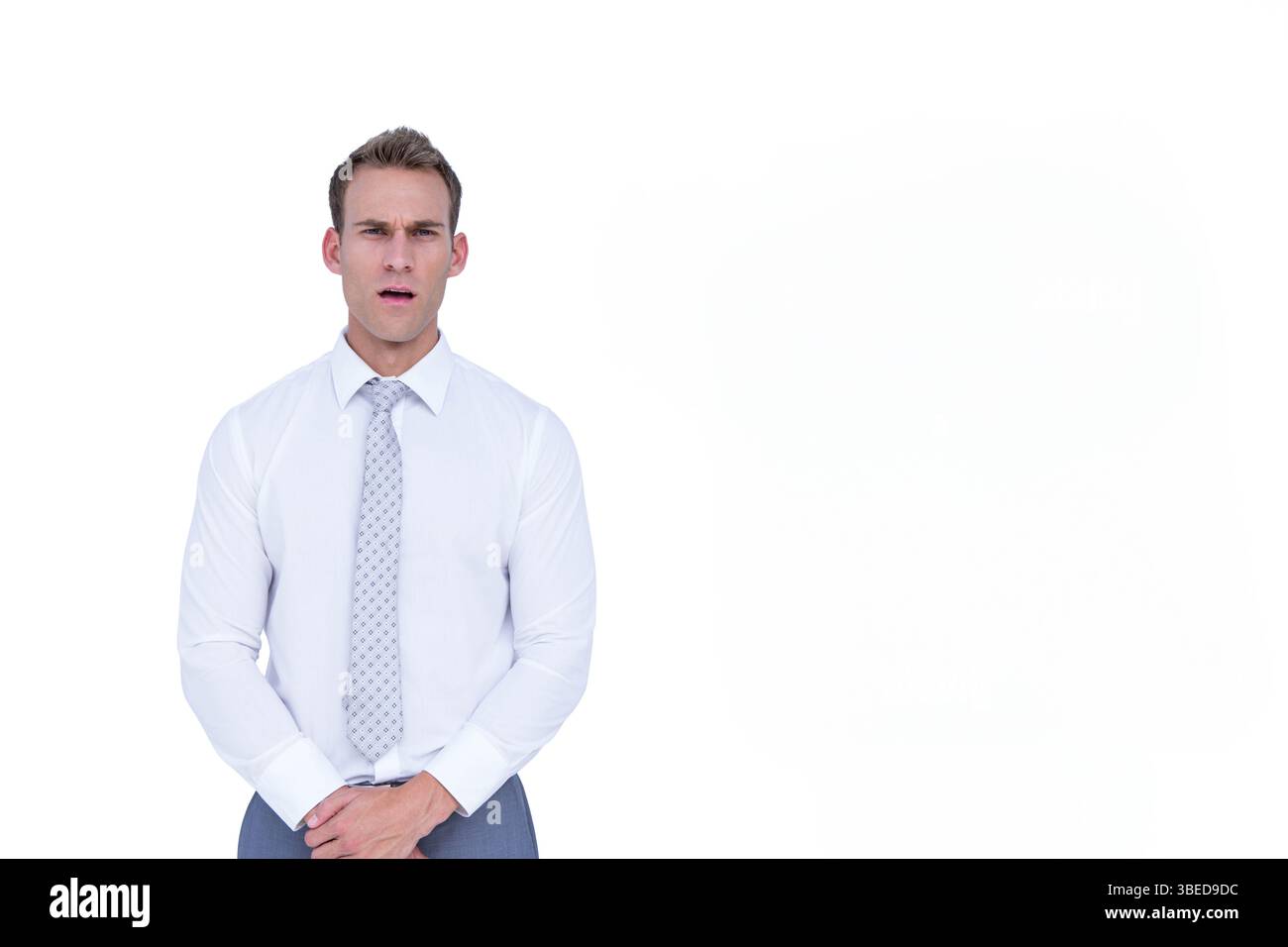 Uomo in piedi sullo sfondo bianco in studio con pantaloni con cravatta grigia e camicia bianca, spazio copia Foto Stock