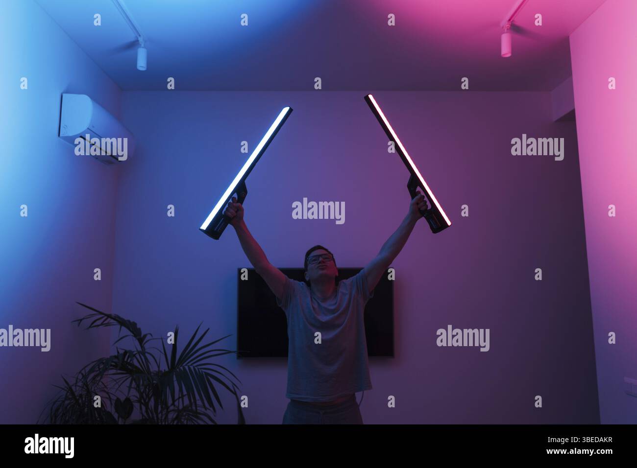 Uomo medio adulto divertente con laser al neon LED a casa, samurai o Jedi. Foto Stock