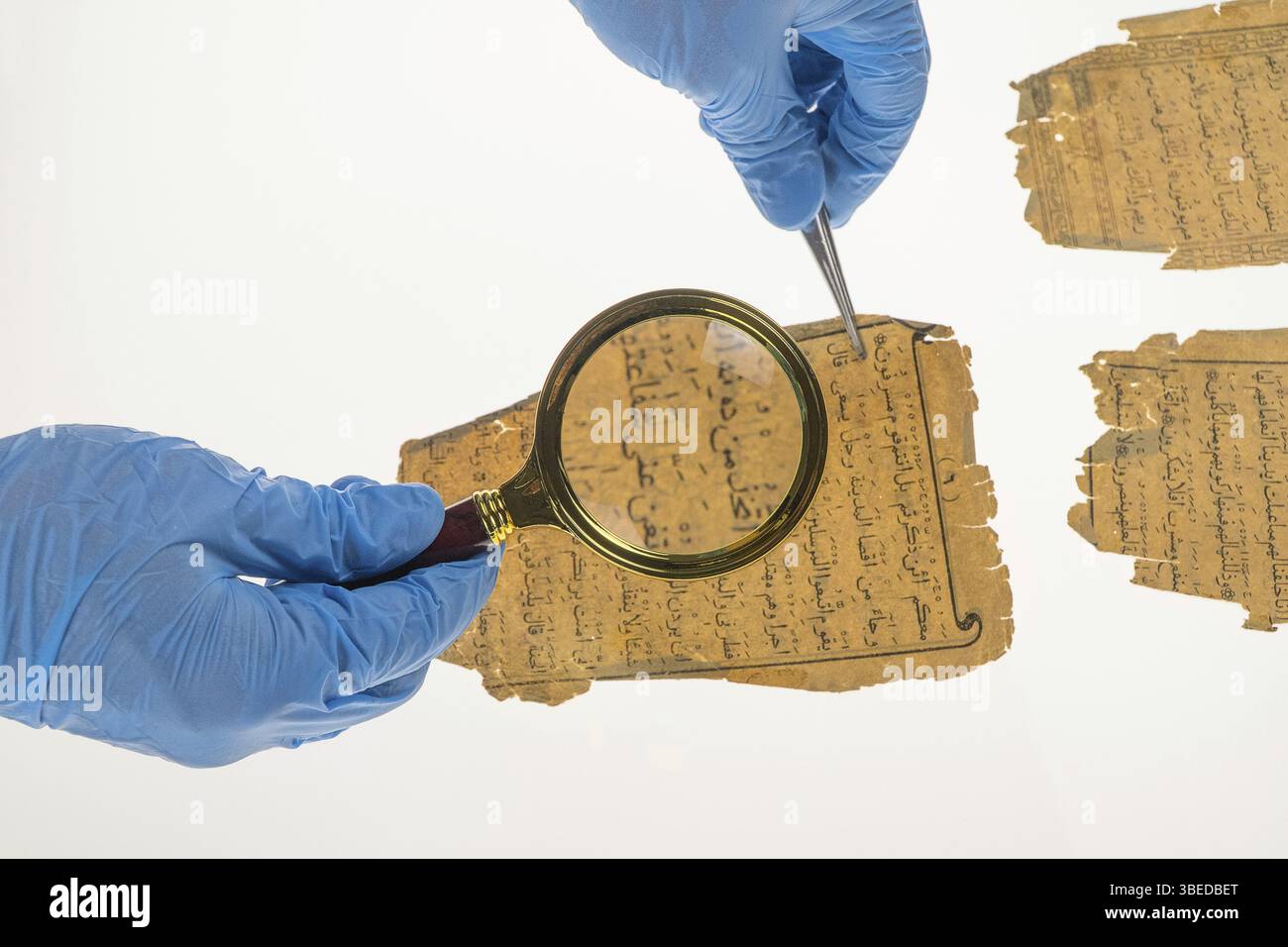 Un ricercatore studia la scrittura araba del Corano utilizzando una lente d'ingrandimento e un tavolo con una luce. Paleografia, lo studio della scrittura araba antica Foto Stock