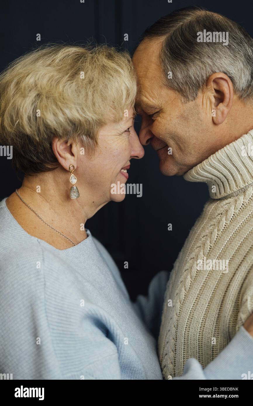 Primo piano ritratto di una vecchia coppia, moglie e marito che sorridono. Sfondo blu scuro. Amanti felici in pensione. Basta con l'età. . Foto Stock