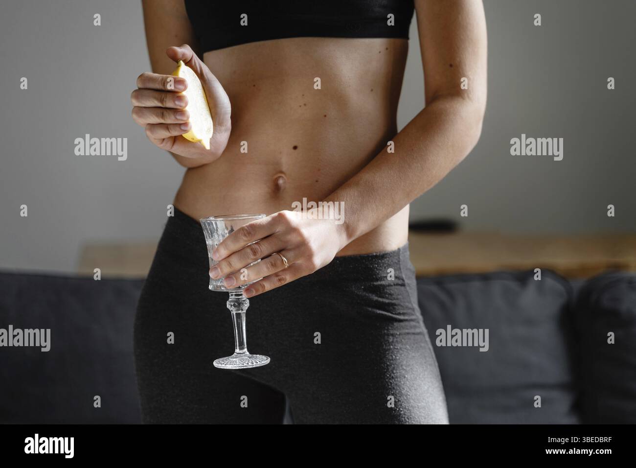 Primo piano di una giovane donna slim-fit che prepara l'acqua con succo di limone. Rituale mattutino. Antiossidante sano. Dieta dimagrante. Aumentare l'immunità e il metabolismo . Foto Stock