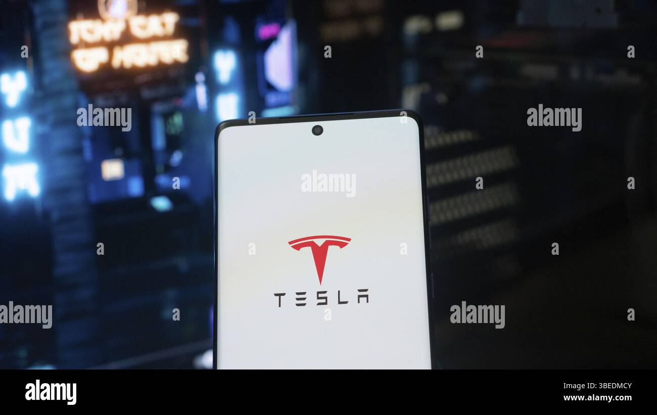 Dhaka, Bangladesh 3 maggio 2025: Logo Tesla sullo schermo dello smartphone e home page del sito wab sullo sfondo sfocato Foto Stock