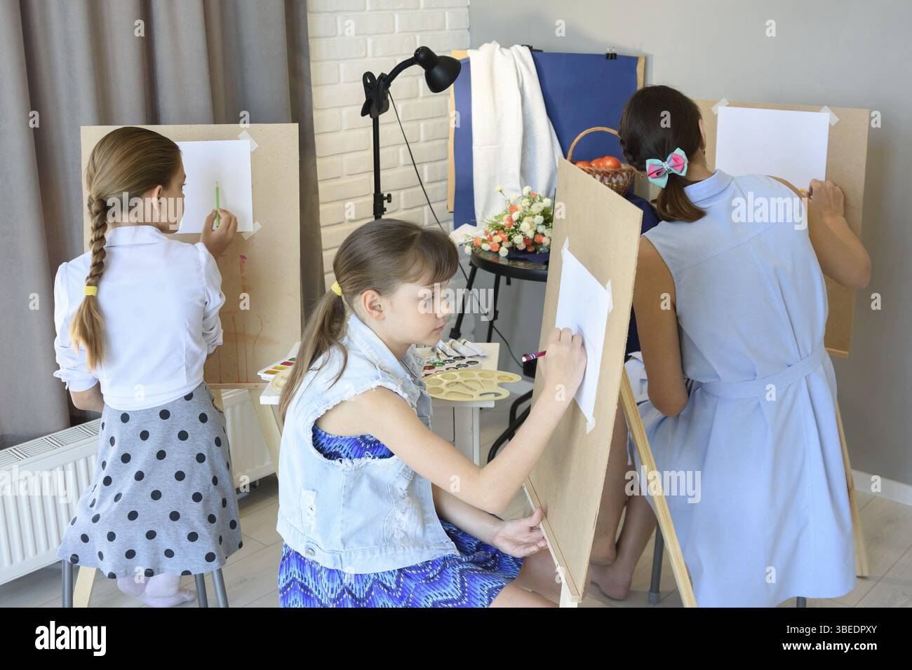 Lezioni nello studio d'arte dietro i cavalletti di bambini e adulti Foto Stock