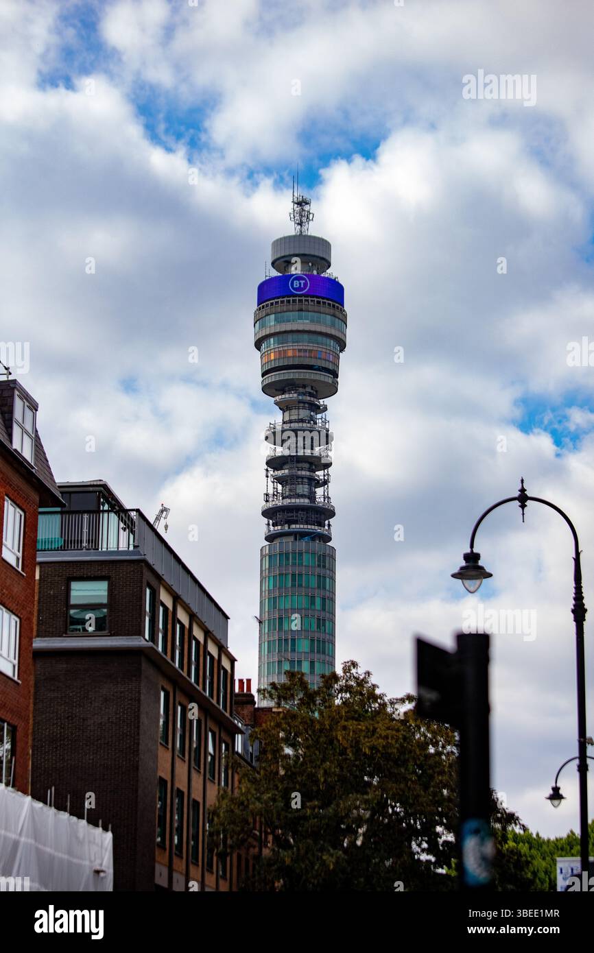 La BT Tower di Londra si erge in modo prominente contro un cielo nuvoloso, circondato da edifici della città. Foto Stock