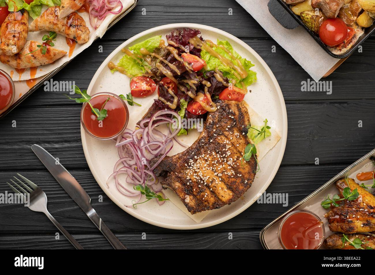 Bistecca di maiale grigliata alla perfezione, servita con colorata insalata di verdure, pomodori ciliegini e cipolle sottaceto. Concetto culinario di cena e cena gustosa Foto Stock