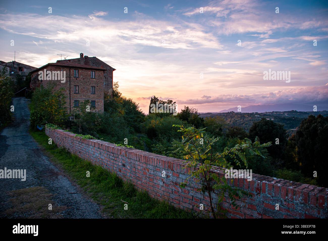 Villaggio toscano abbandonato al tramonto, immerso nella calda luce dorata, circondato da colline ondulate e dalla natura silenziosa, evocando una bellezza senza tempo. Foto Stock