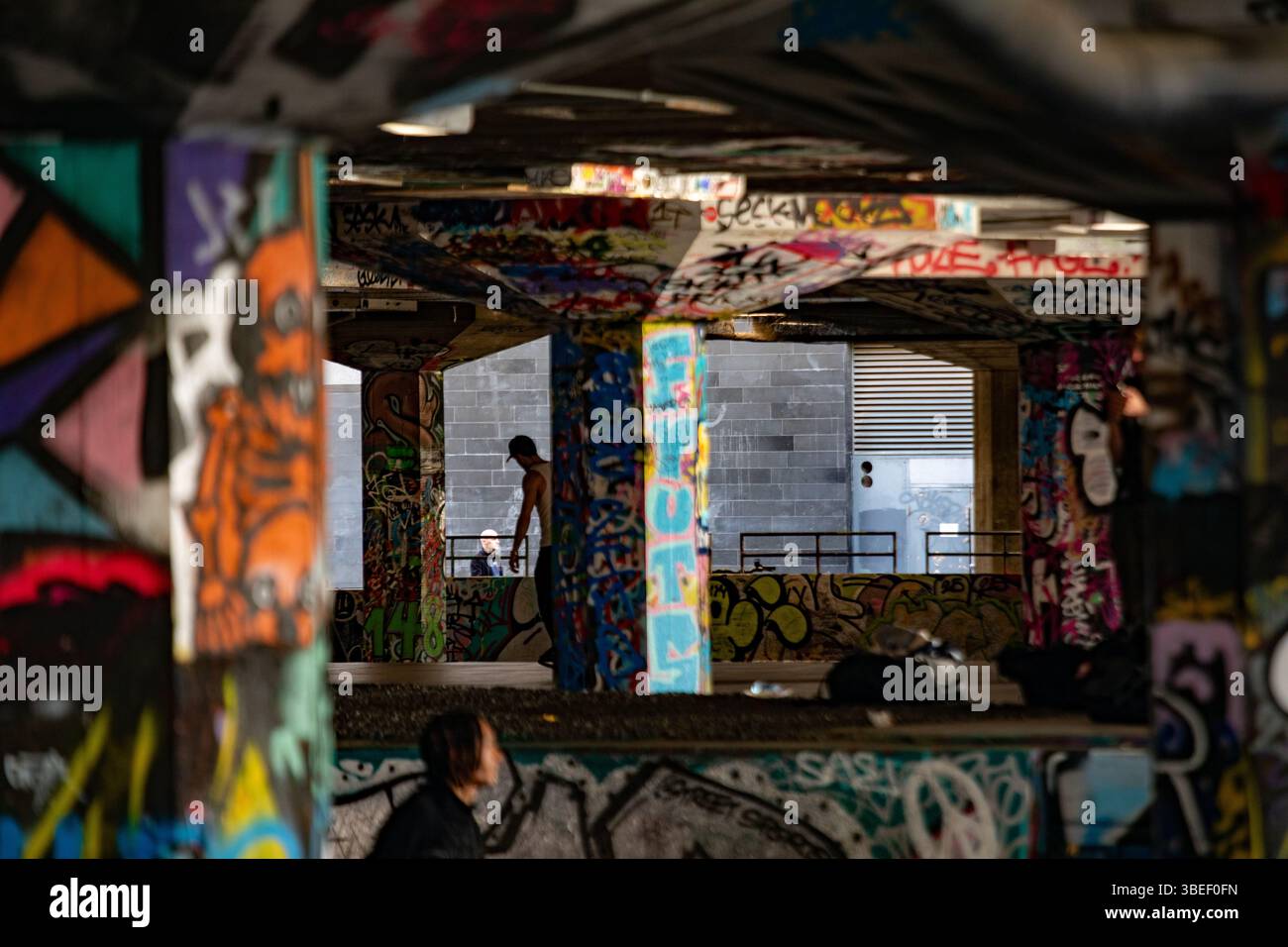 Un vivace sottopassaggio coperto da graffiti a Londra è un luogo popolare per lo skateboard. L'arte urbana riempie lo spazio di espressioni colorate. Foto Stock