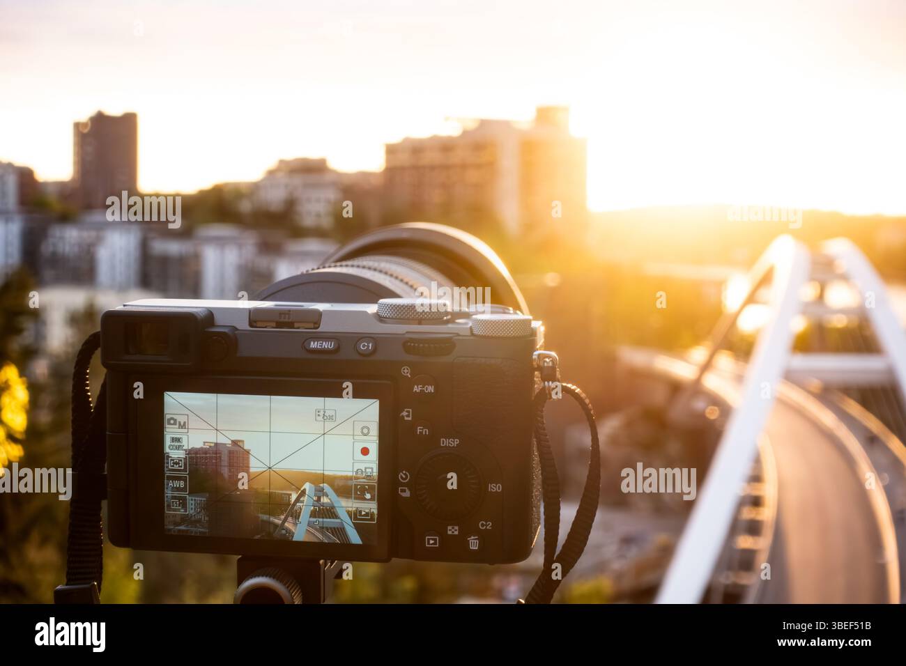 Fotografia professionale con una fotocamera su un treppiede che fotografa un paesaggio urbano al tramonto contro il sole per un concetto di hobby Foto Stock