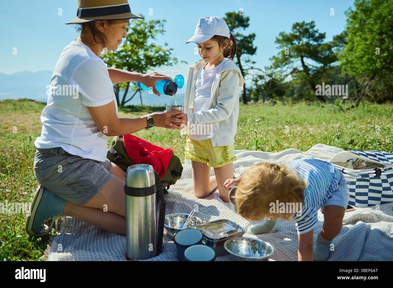 Tempo libero in famiglia durante un picnic in una radiosa giornata estiva in montagna. Un genitore e i bambini condividono un momento di legame in mezzo a una natura pittoresca Foto Stock