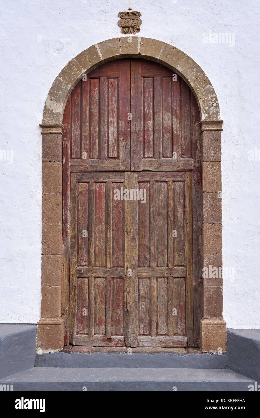Vecchia porta marrone della chiesa in legno in un portale rotondo in pietra Foto Stock
