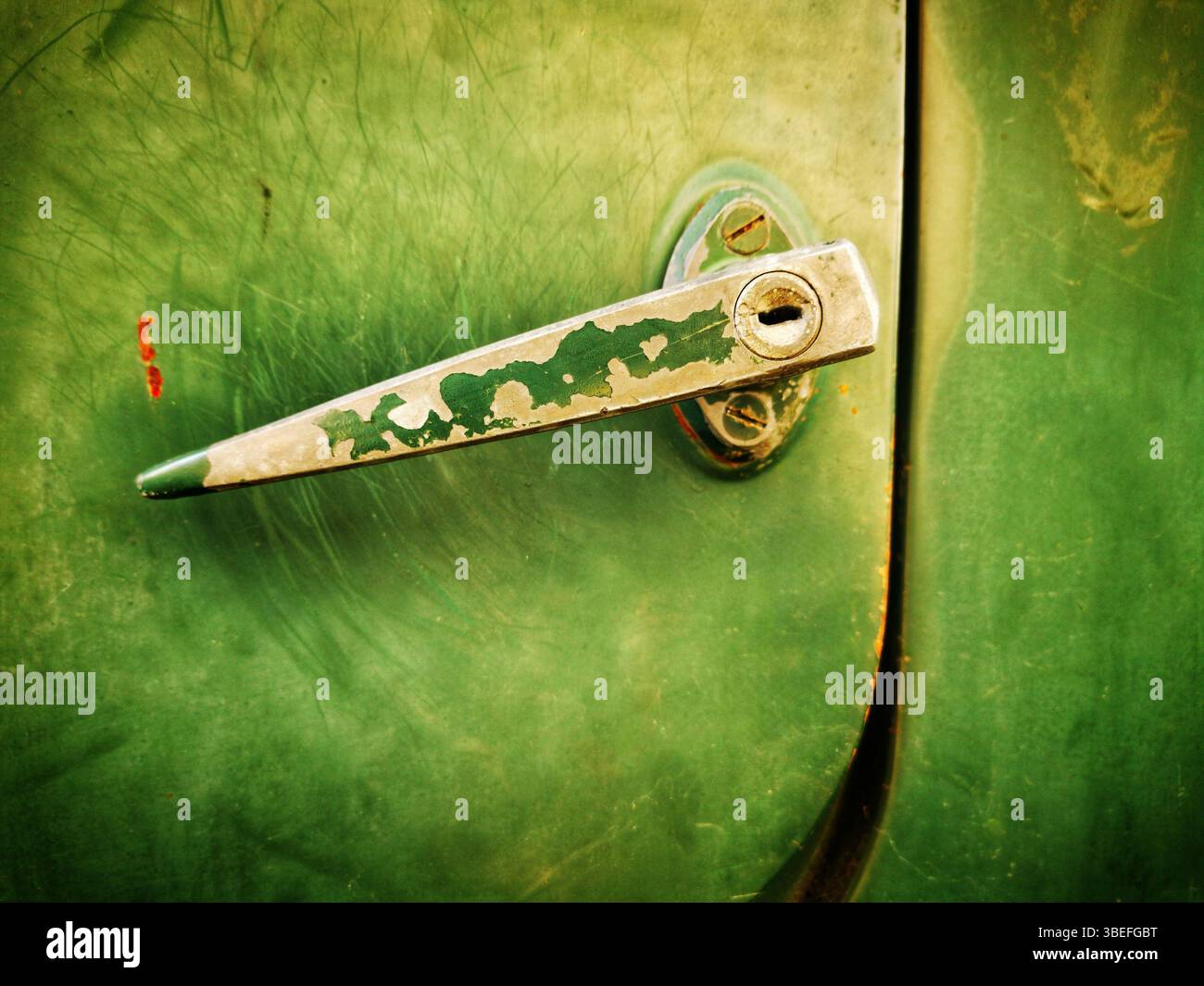 Vista ravvicinata della maniglia di una portiera di un'auto d'epoca con superficie intemprata e vernice verde brillante. Foto Stock