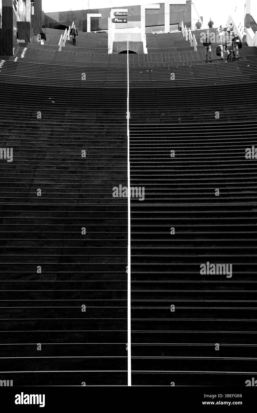 Vista simmetrica in bianco e nero della grande scalinata della stazione di Kyoto, evidenziata dalle silhouette dei pendolari in alto Foto Stock
