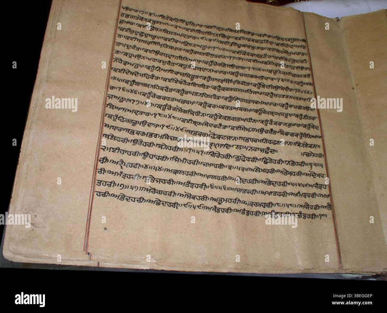 Questo manoscritto storico del Guru Granth Sahib, originario del XVII, XVIII o XIX secolo, include linee nere e rosse che segnano i margini, una caratteristica trovata in molti manoscritti Sikh del periodo. Foto Stock