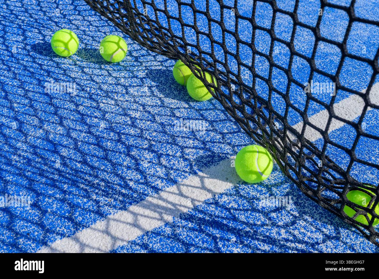 primo piano di rete da campo per padel e palline sparse colori vivaci di un campo da tennis all'aperto Foto Stock