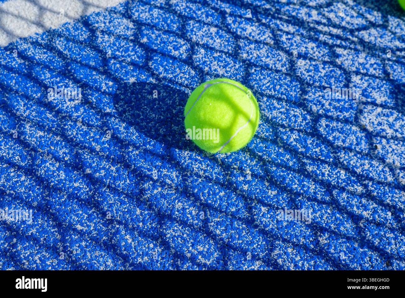 composizione dinamica di attrezzature padel che mostra l'ombra geometrica della rete sul campo Foto Stock