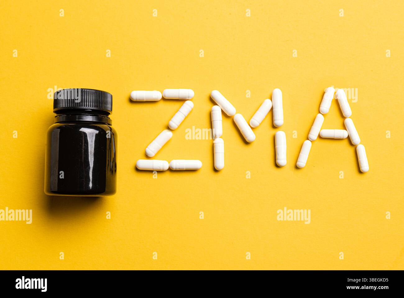 Capsule integratore ZMA e contenitore in plastica su sfondo giallo, vista dall'alto. Supplemento sport per recupero notturno. Foto Stock