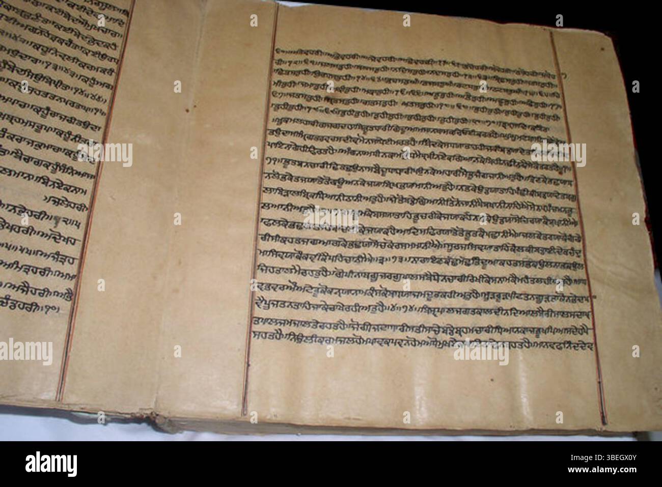 Questo manoscritto storico del Guru Granth Sahib, risalente al XVII, XVIII o XIX secolo, presenta linee di contorno nere e rosse, una caratteristica distintiva nei manoscritti religiosi Sikh. Foto Stock
