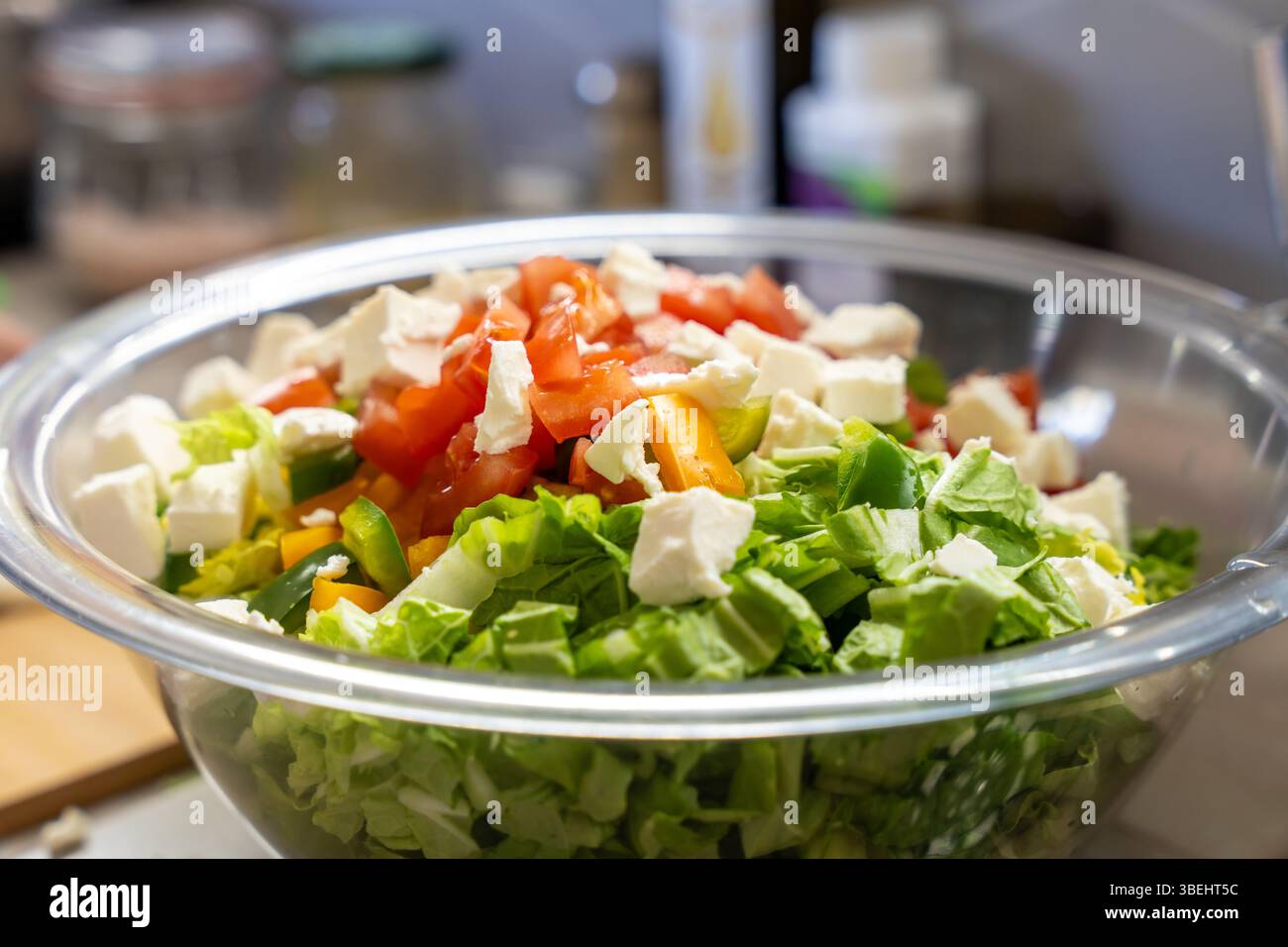 Ciotola di vetro riempita con insalata di verdure fresche condita con pomodori a dadini e formaggio bianco, per un'alimentazione pulita e uno stile di vita sano Foto Stock