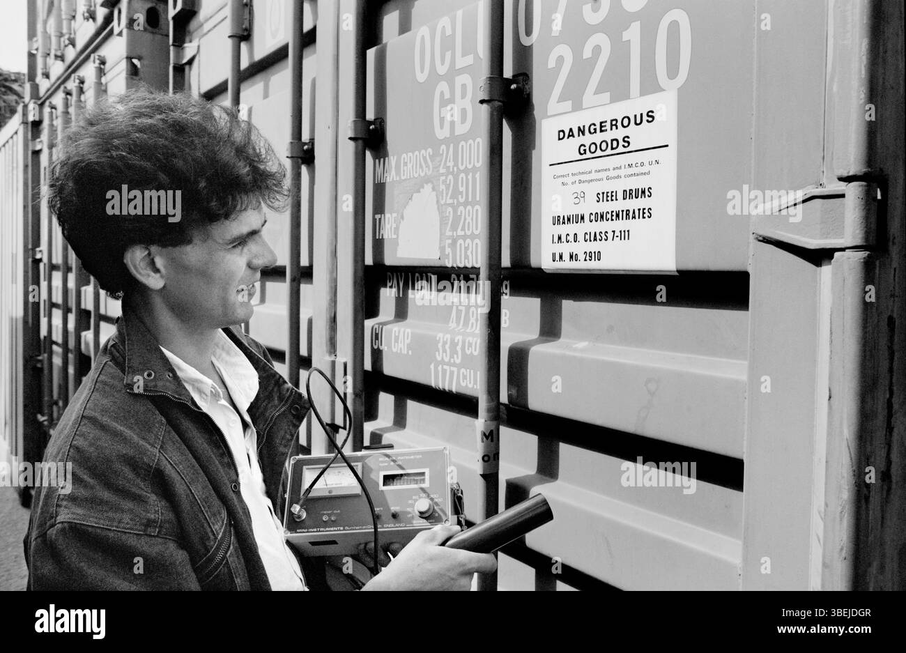 Un attivista anti-nucleare con un contatore Geiger che controlla un contenitore di minerale di uranio scoperto da attivisti anti-nucleari al porto di Southampton. Foto scattata nel 1988. Foto Stock
