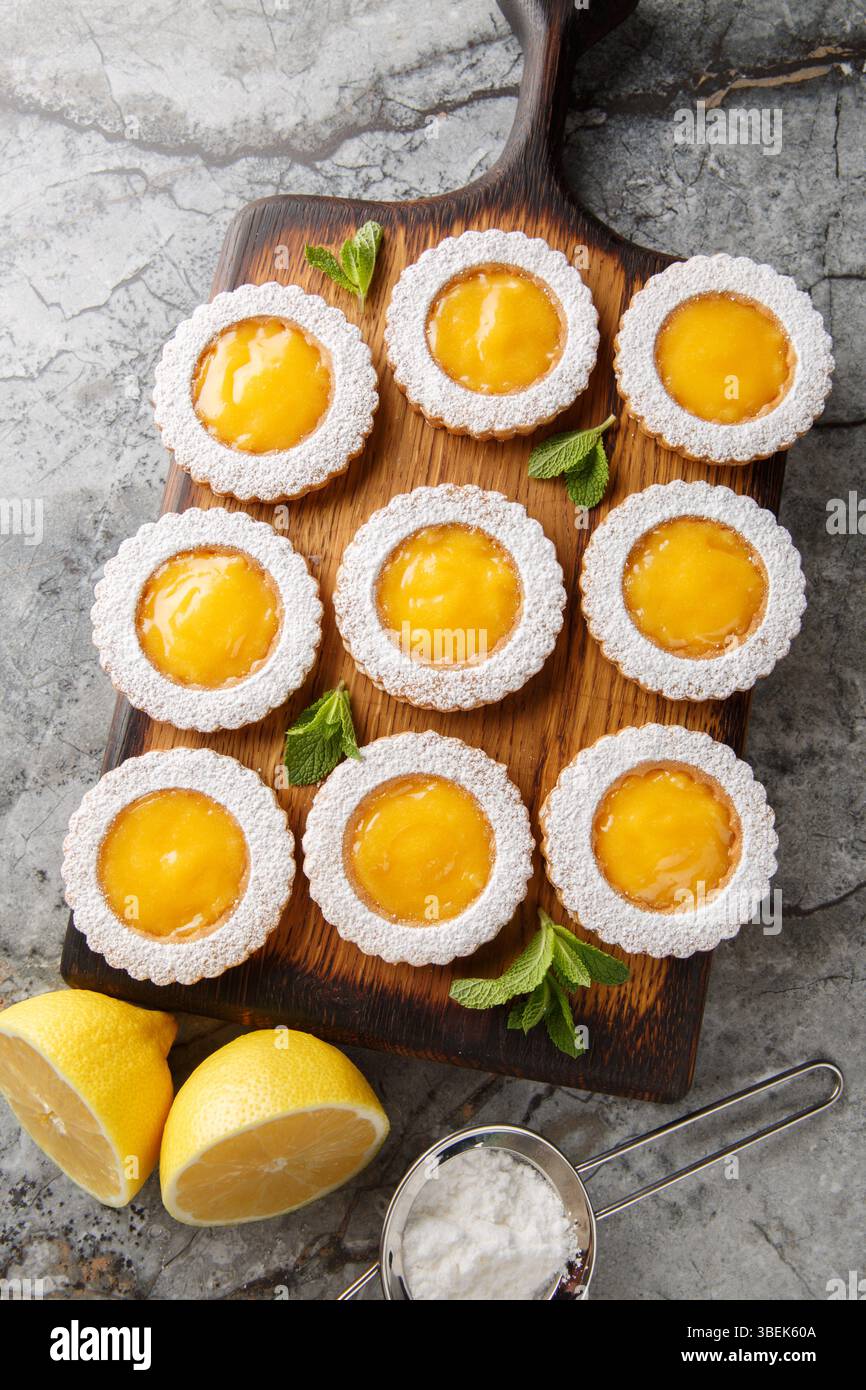 Deliziosi biscotti dolci al limone cosparsi di zucchero a velo sul tavolo. Vista dall'alto verticale Foto Stock