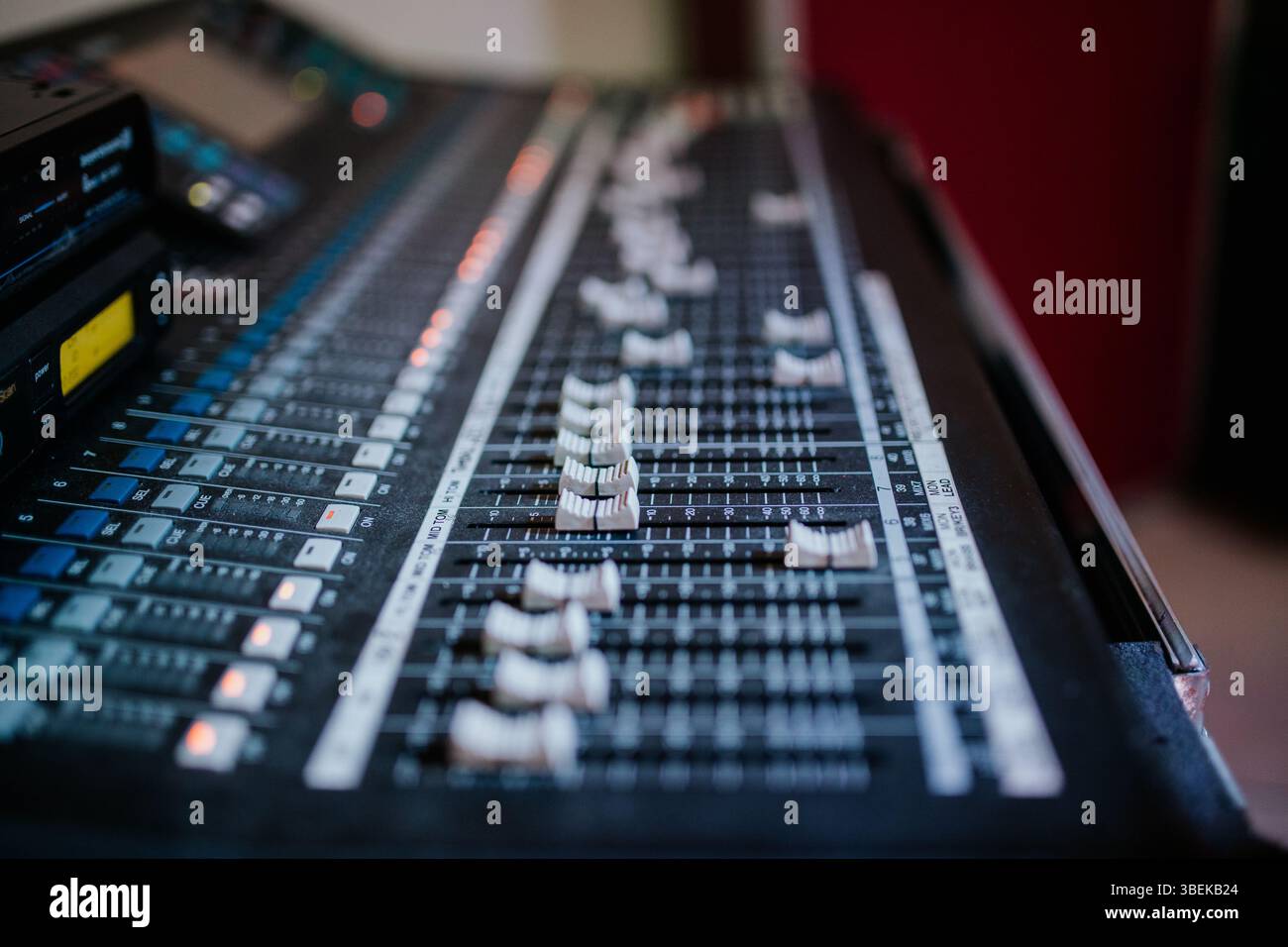Visualizzazione dettagliata di una console di missaggio audio con cursori e pulsanti luminosi, utilizzata per la produzione musicale e il controllo audio dal vivo. Foto Stock