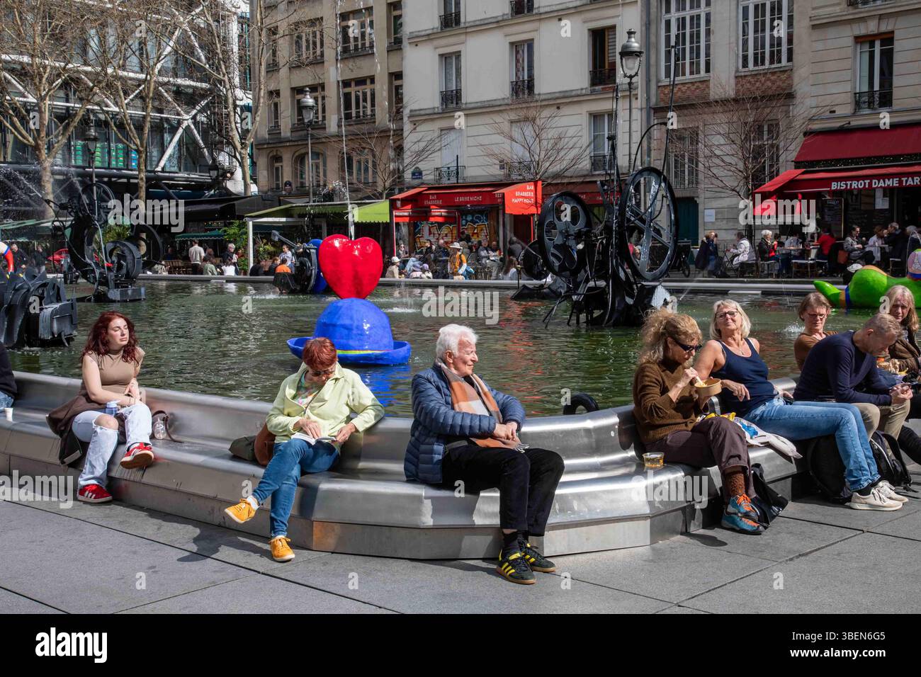 Persone che si rilassano presso la Fontana Stravinsky in Place Igor Stravinsky in una giornata di sole nel quartiere Marais di Parigi, Francia Foto Stock