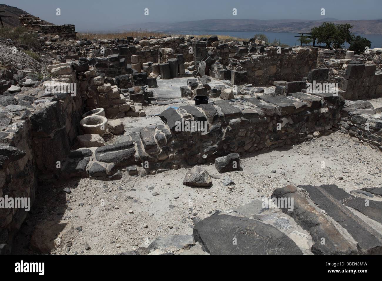 Sussita, Hippos, sale laterali parti della chiesa nord-orientale, costruita con pietra basaltica locale, rovinata da un terremoto nel 749 Mare di Galilea visto nel retro. Foto Stock