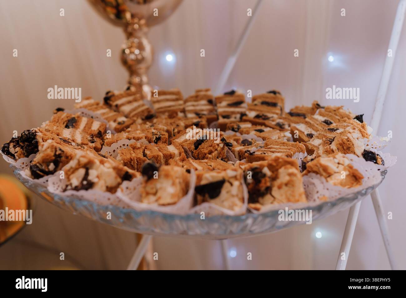 Un incredibile dessert baklava a più strati presentato su un piatto d'argento decorato sotto una luce soffusa, che mostra le sue sfumature dorate-marroni e il delizioso te Foto Stock