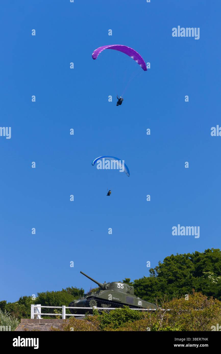 Due parapendio sorvolano il memoriale dei carri armati Sherman M4A2 ad Arromanches-les-Bains, Calvados, Normandia, Francia Foto Stock