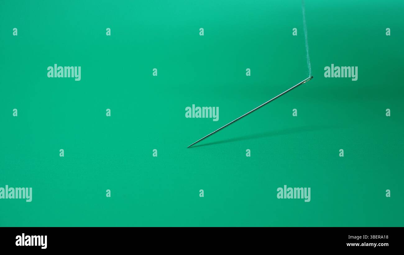 Ago da cucire isolato lateralmente in verde. Foto Stock