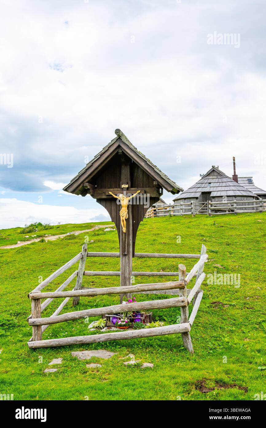 Crocifisso sul prato delle alpi slovene, vicino al pascolo. Religione simbolo cristiano, i pascoli sullo sfondo. Foto Stock