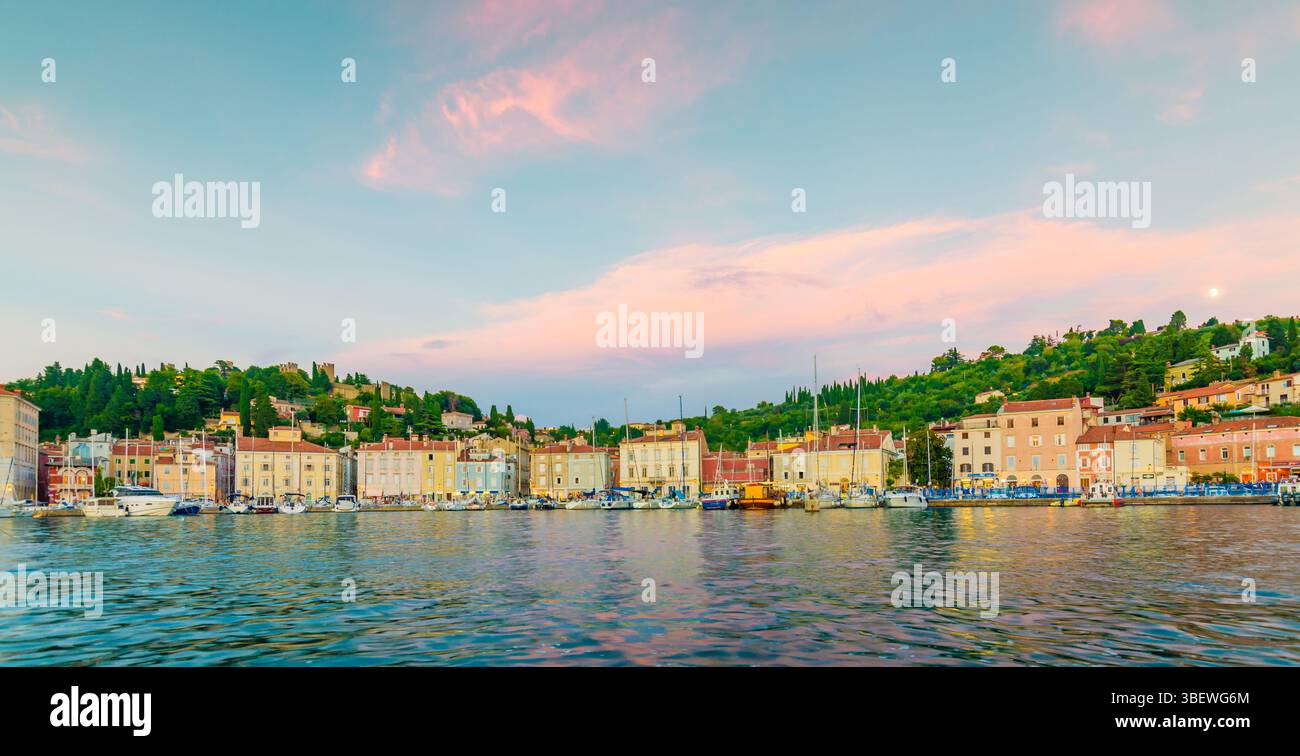 Porto di Pirano durante il tramonto. Luce soffusa e calda sopra le barche e le case dei pirati Foto Stock