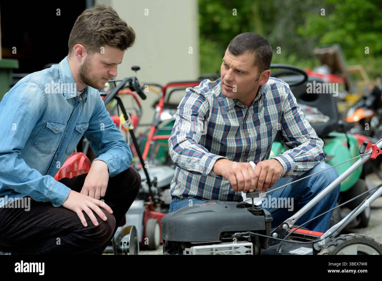 apprendista e uomo che ripara il motore della taglierina Foto Stock